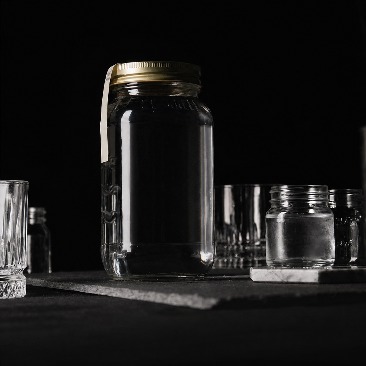 Speakeasy moonshine room with mason jars and glassware on a dark surface